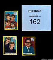 Close-up of three Vlinder celebrity cards featuring The Beatles, The Everly Brothers, and Roy Orbison with a MaxSold tag.
