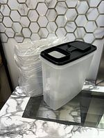 Two translucent plastic cereal containers with black lids showing dual opening mechanisms.