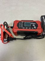 Front view of the red and black 12-volt 6-amp battery charger with clamps and power cord attached.