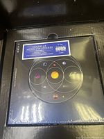 Top view of the box opened to show the CD and inner cover art featuring planets and orbits along with track listing information.