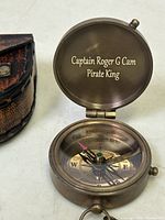 Top view of brass compass open showing engraved lid and compass face with directional markings.