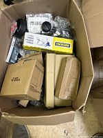 Top view of box showing multiple cardboard boxes, including a yellow MOOG box and a box labeled Joy Tutus, with loose and plastic-wrapped hardware parts inside.