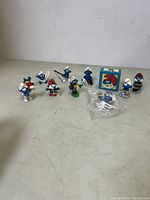 Lot of 10 Smurf character figurines arranged on a surface with one in original packaging and one sealed in a plastic bag.