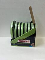 Seven rolls of green translucent glow in the dark brick-patterned tape in branded box displaying front and side views.