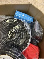 Box showing black and white spiral fabric mats, small blue Umbra box, red TradeSafe bag, various packed components.