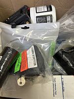 Box showing multiple items including black tool, white jar, and coiled wire in plastic bags.