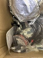 Various new and some used miscellaneous items inside a box, including a folded metallic sheet, plastic and metal small parts, and instructional sheet.