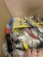 Box with hardware and electrical components, both packaged and loose items visible