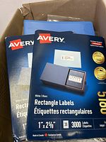 Two packs of Avery white rectangle labels in unopened packaging inside the box.