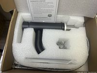 Faucet and accessories nestled in white foam packaging inside a cardboard box, showing pop-up drain and supply lines.