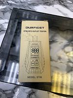 Photo of the front of the beige box packaging showing the Durfcst ST06 GFCI outlet tester illustration and text.