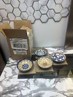 Four Williams Sonoma mini spice bowls displayed on cardboard with one shipping box behind them on a marble surface