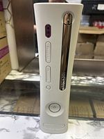White Xbox 360 console front view show power button, disc drive, and USB ports.