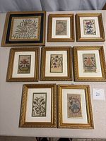 Top-down view of the eight framed Turkish needlepoint artworks arranged on a table, showing detail and frame style.