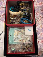 Closer top view of some bracelets and bead strands in cream, turquoise, black, gold, and blue tones inside jewelry box.