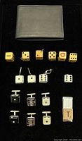 Photo showing black leather wallet, 7 yellow vintage wooden dice charms with letters and numbers, 4 white dice charms with metal loops, 8 sterling silver square cufflinks and one rectangular item with T and 1 markings on it.