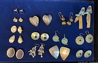 Overview image showing all 14 pairs of earrings arranged on a display board, variety of styles visible.