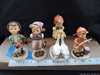 Lot of four Hummel figurines shown on ruler for size