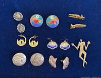 Top view showing all earrings and brooch pieces on blue background, displaying design and colors clearly.
