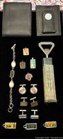 Photo showing full lot with wallets, bracelet, pendants, cuff links, bottle opener, and license plate tags laid out on black cloth