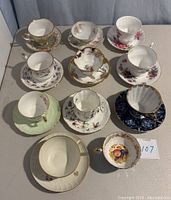 Top-down view of all teacup and saucer sets featuring floral and gold designs, showing variety and some broken handle inside a cup.