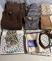 Photo of assorted Worth brand clothing items laid out, including knitwear, pants, scarves, jewelry, and belts.
