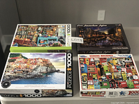 Four boxed jigsaw puzzles arranged in two rows showing titles and artwork on boxes.
