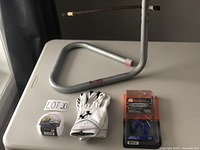 Photo of the lot showing kicking tee, Under Armour football gloves, and two mouthguards in packaging on a table.