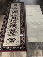 Full view of the burgundy floral carpet runner with the separate underpad beside it on a hard floor.