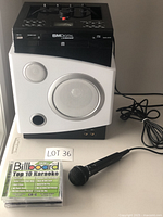 Full view of karaoke machine on table with microphone and 4 karaoke CDs in front.