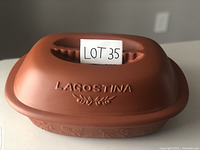 Top view of brown clay roaster lid with embossed LAGOSTINA branding and decorative wheat motif.