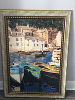 Front view of framed Mediterranean coastal print showing boats on water and village buildings under a golden and textured frame.