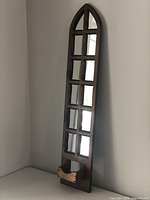 Front view of long wooden decorative mirror showing multiple mirror panes in grid within arched frame and small shelf at bottom