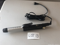 2-in-1 Rowenta ceramic curling and straightening iron shown folded with power cord coiled beside, placed on white surface with lot card