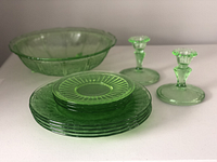 Four 9-inch plates stacked beneath four 6-inch plates, one 10-inch bowl in the back, and two candlestick holders at side.