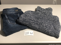 Two items folded on a table: a navy blue and white knitted turtleneck sweater and a pair of dark blue denim jeans.