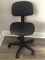 Front view of black adjustable rolling desk chair showing fabric seat and backrest, five caster wheels, and adjustable height mechanism.