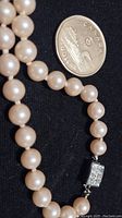 Pearl necklace next to a Canadian dime for scale, showing round pearls and rectangular rhinestone clasp with wear.