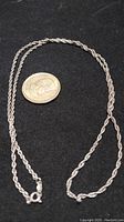 24-inch sterling silver rope chain necklace laid flat beside a US quarter for scale, showing the full chain and clasp.