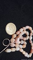 Close-up image of necklace with Andes opal beads beside Canadian dollar coin for scale.