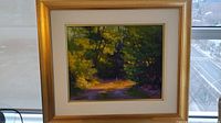 Overall view of framed painting showing gold-tone frame, white mat and forest path scene