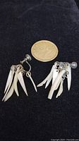Pair of vintage screw back earrings with mother of pearl dangles displayed with a coin for size comparison.