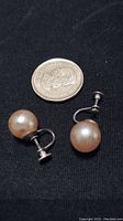 Pair of vintage screwback earrings with faux pearls next to a coin for scale, showing size and detail of wear.
