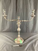 Front view of vintage three-arm candle holder candelabra with silver tone finish on black cloth background and Sharpie marker for scale.