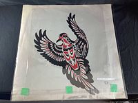 Photo of vintage First Nation Haida Gwaii art print featuring stylized bird in red, black, and white on paper showing folds and age wear.