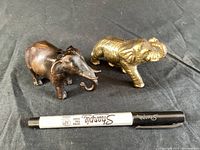 Pair of metal elephant figurines with a Sharpie marker for scale, showing a darker brown elephant and a gold-toned elephant.