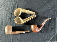 Two wooden pipes with a leather pipe case on a black fabric background