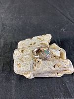 Front angle view of the vintage sterling silver ring with marcasite and focus on the green center stone. Displayed on a porous rock object.