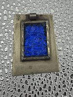 Front view of rectangular sterling silver pendant with deep blue textured glass center, showing loop bail at top.