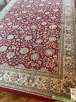 Close-up showing red base with beige and cream floral motifs and beige border with dark blue accents.